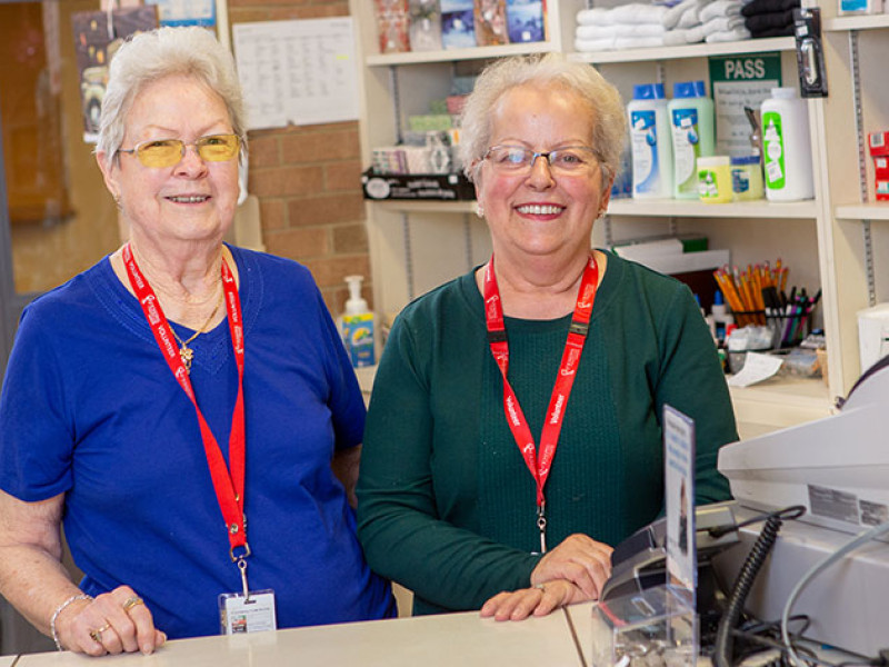 two women standing at the counter of the store where they volunteer