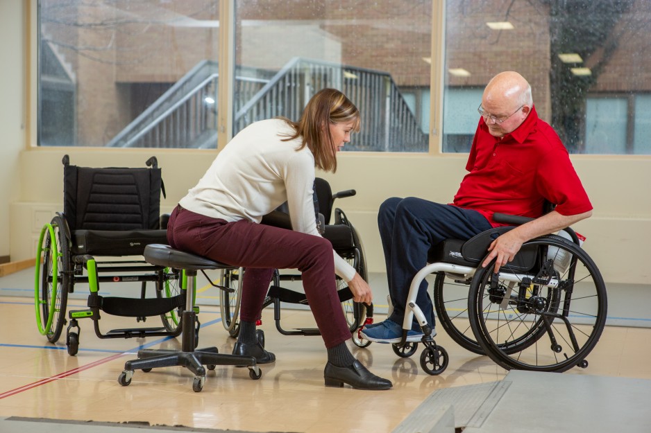 A rehabilitation caregiver helps a patient with his wheelchair.