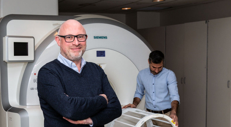 Researcher stands in front of MRI machine