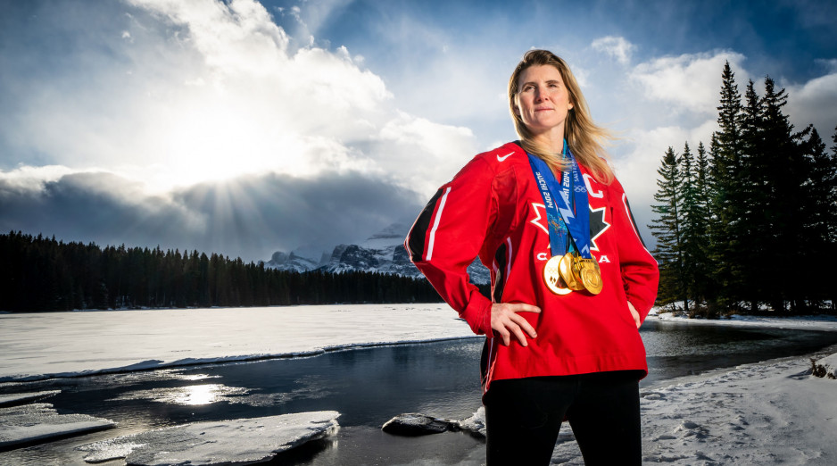 Haley Wickenheiser wearing hockey jersey and medals with sun streaming through the clouds behind