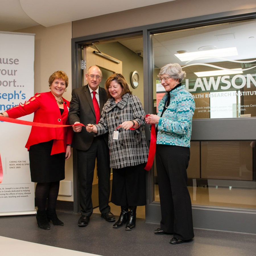 group of people cutting a red ribbon at centre opening