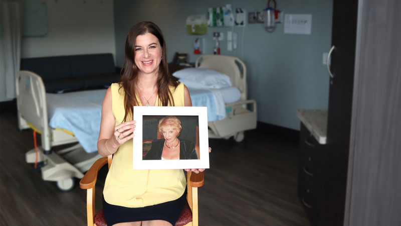 woman holds up a portrait photo of her late mother