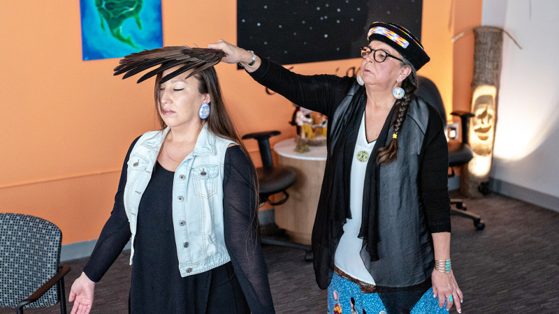 An Indigenous women holding a feather over the head of a female Indignenous patient