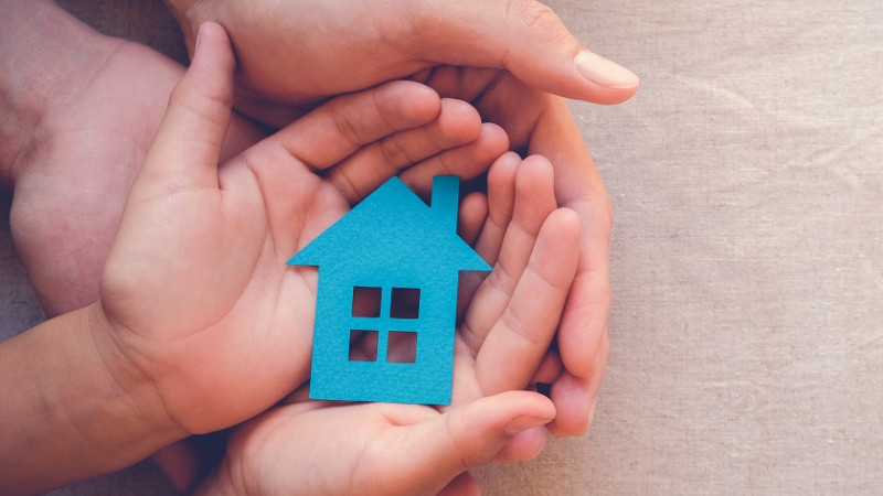 Hands holding a house-shaped figure