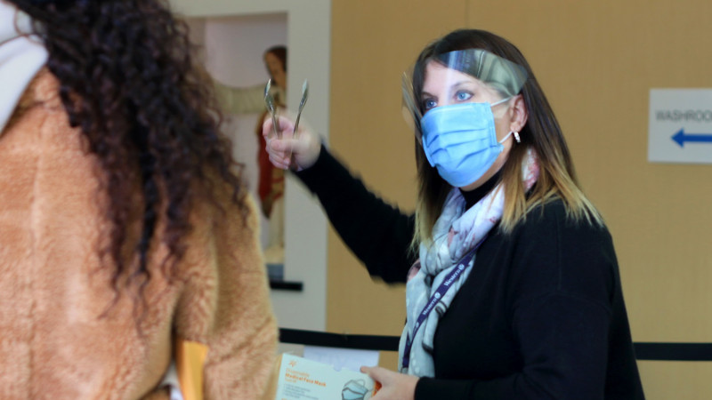 woman wearing surgical mask directs visitor