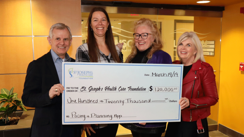 four people hold up a large cheque