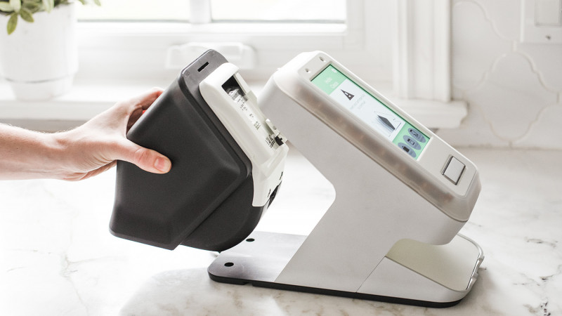 hand grasping back of smart home technology device with data input pad mounted on a stand