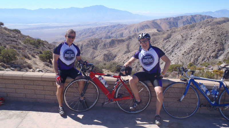 Two men pose for scenic photo with their bicycles