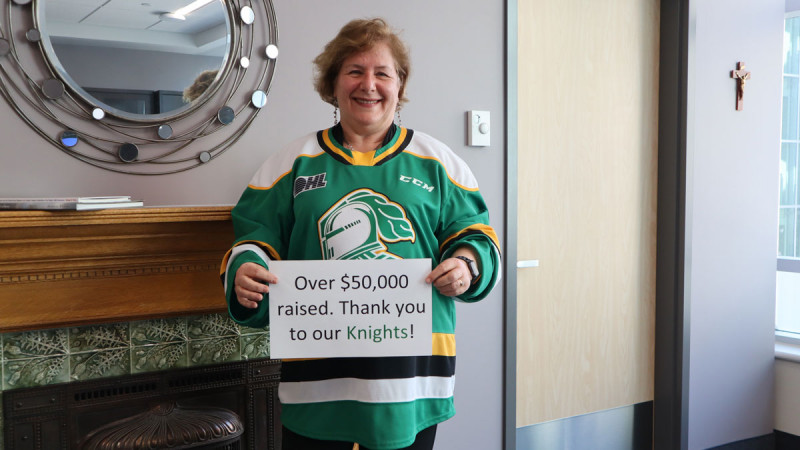 Dr Gillian Kernaghan wears a London knights jersey and holds up a sign thanking the hockey team