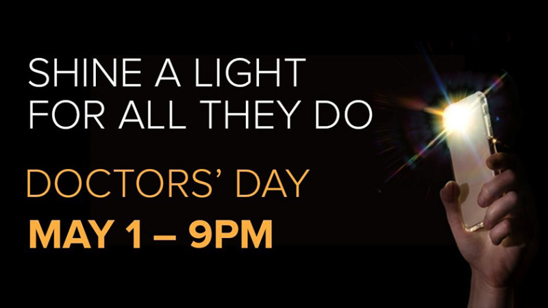 hand reaching upward from the dark, holding a lit cell phone flashlight with "Shine a light for all they do on May 1 at 9 pm" text