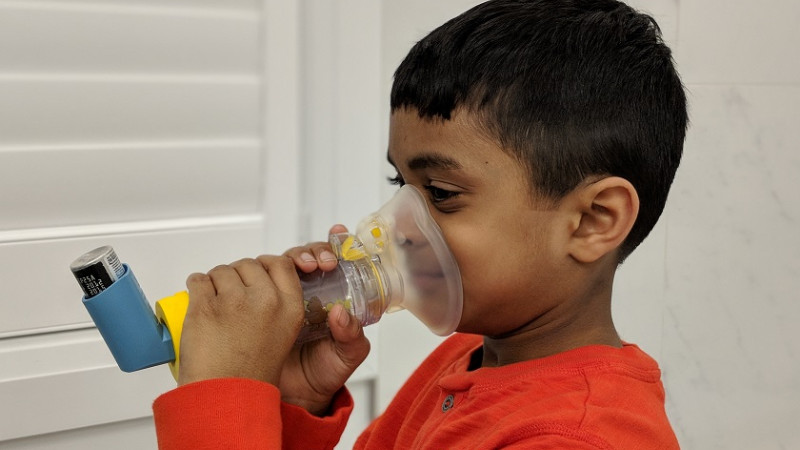 boy breathing into an asthma inhaler