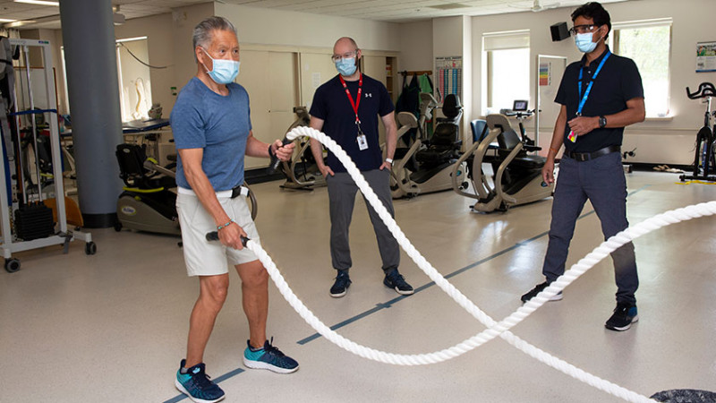 Stroke patient Michael Kan doing rehabilitation rope exercises with physiotherapists supervising