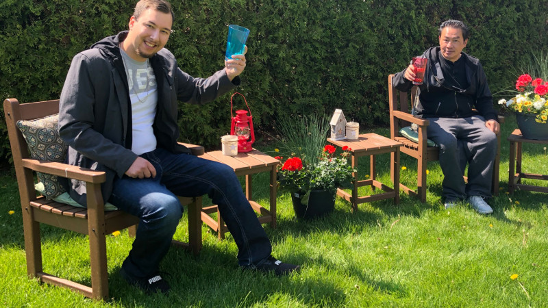 two men raising their drinks while sitting outside