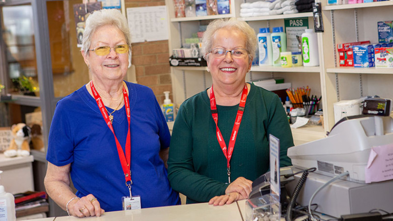 two women standing at the counter of the store where they volunteer