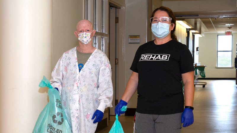 Jenna and Bonnie Haynes standing in a hallway at Parkwood Institute, holding bags of linens