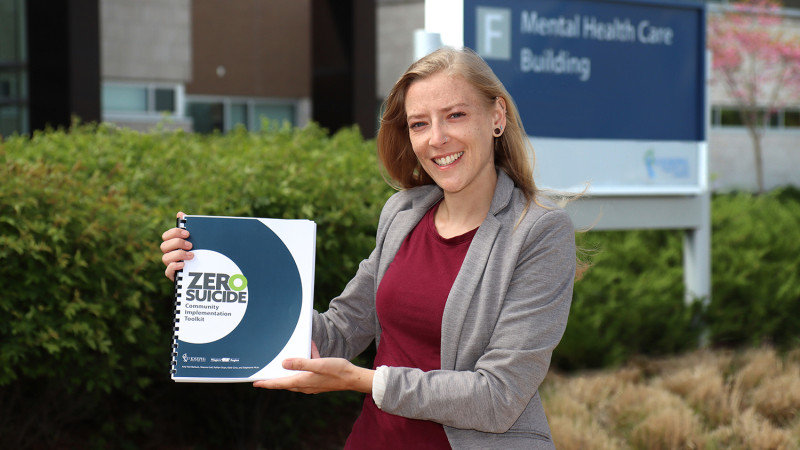 Shauna Graf holding a copy of the Zero Suicide Community Implementation Toolkit