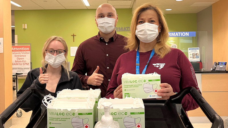 three staff members wearing masks, holding the boxes containing the new bio masks
