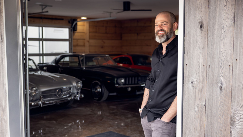 Ryan Finch standing in his garage with vintage cars