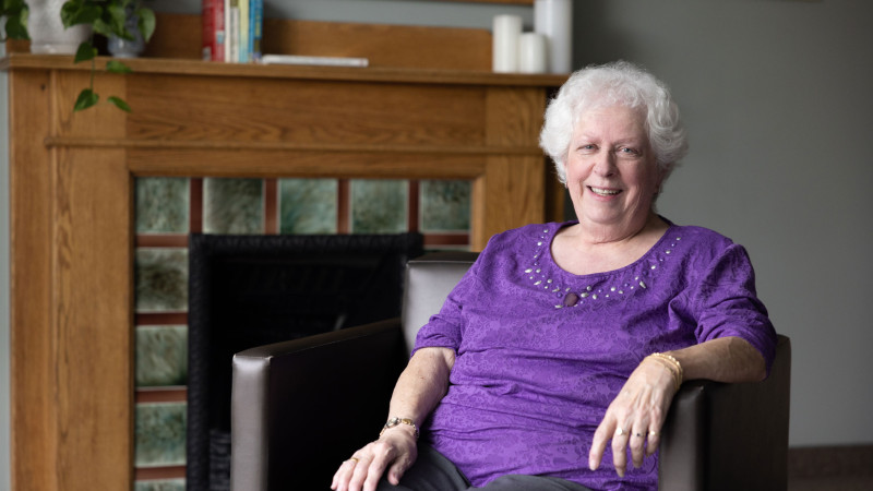 Nancy sits near a fireplace