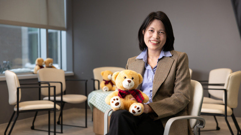 Dr. Wong Serena sitting down holding a teddy bear.