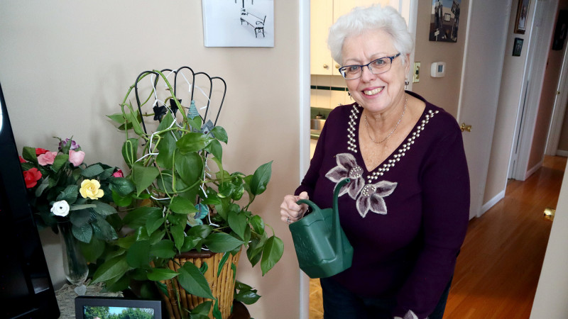 Lynda Vanderaa standing in her home, watering plants