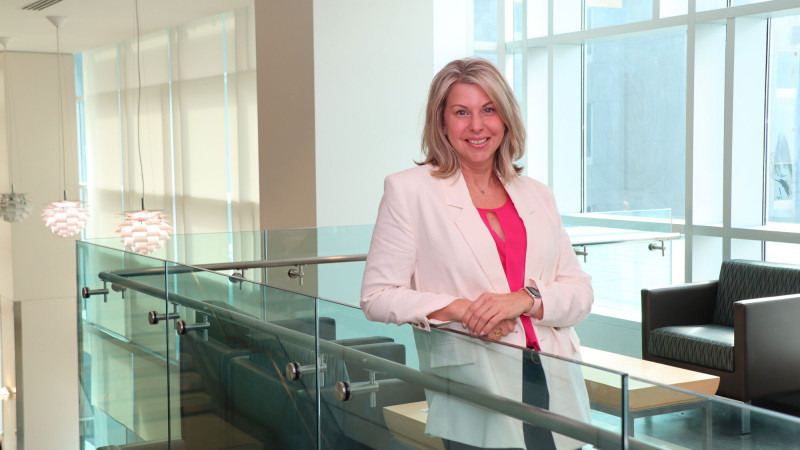 A woman (Tricia) leaning up against a glass railing