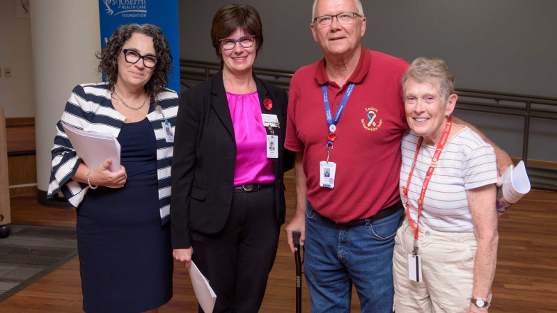 three women and one man standing together and smiling