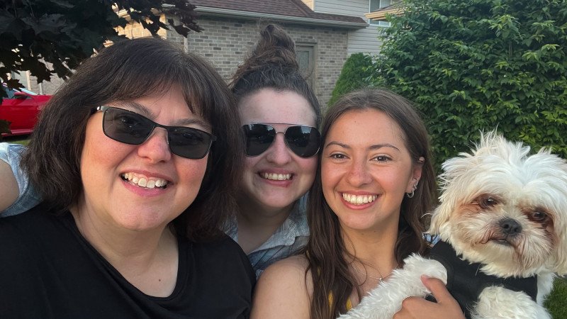 Three women and a dog smile at camera