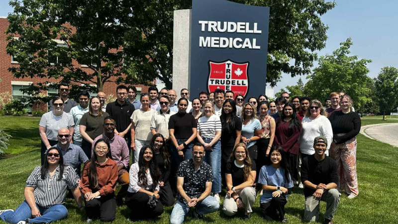 Trudell employees posing for a photo on a grassy area in front of Trudell building