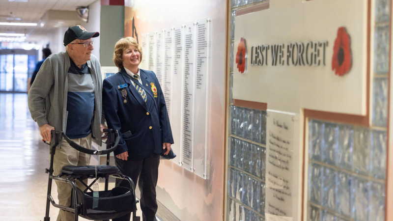 Two individuals look at the Hall of Heroes wall