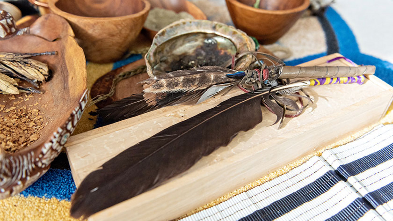 objects used in Indigenous healing ceremonies: eagle feather, wooden bowls and a shell full of medicines for smudging