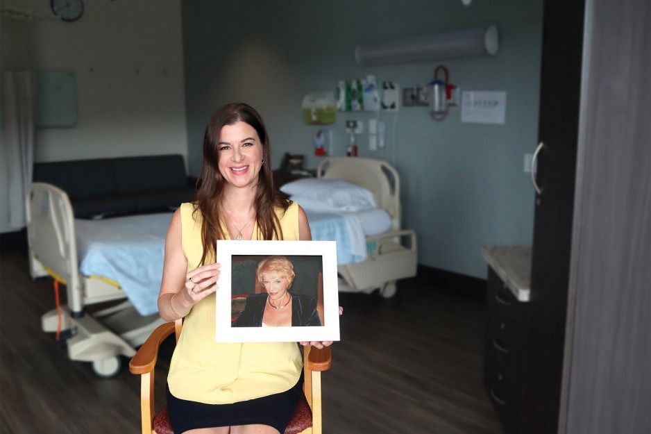 woman holds up a portrait photo of her late mother