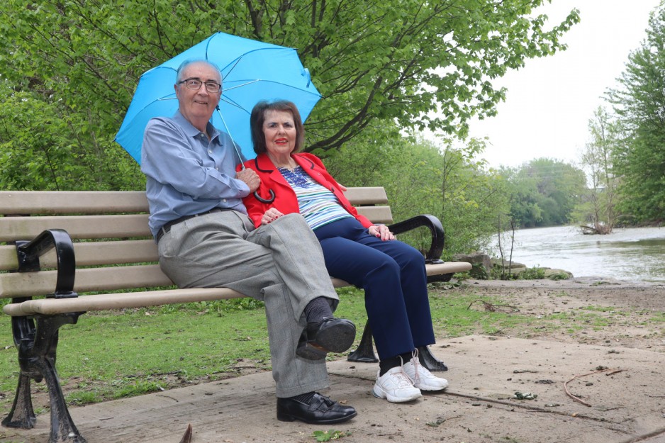couple sitting on a park bench with an umbrella