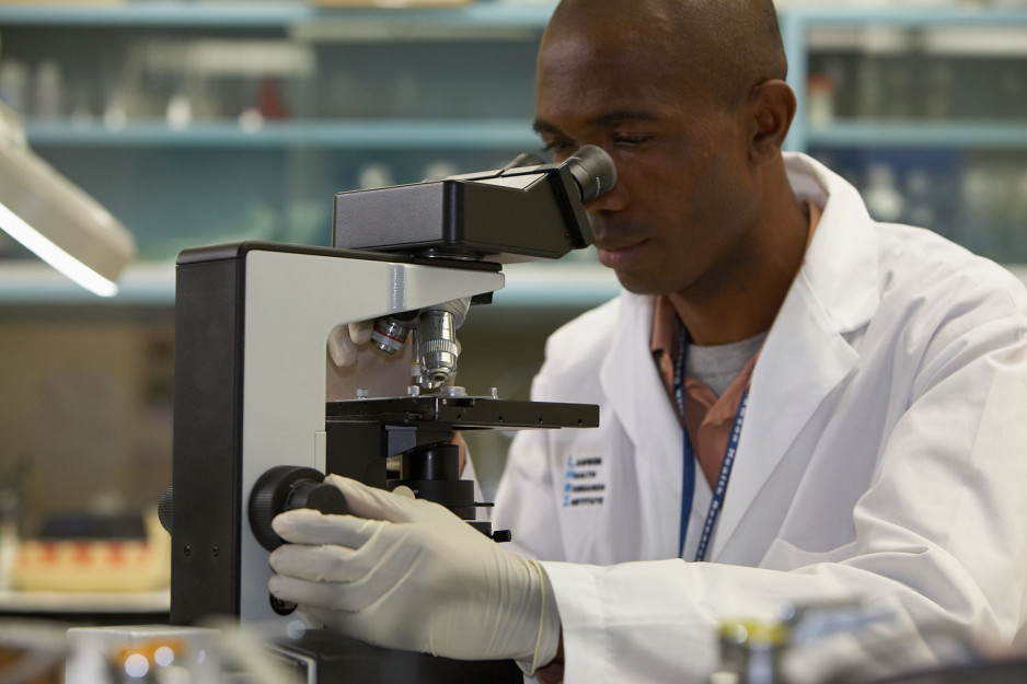 scientist looks through a microscope