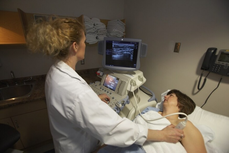A patient undergoes an ultrasound on their breast with the help of an ultrasound technologist.