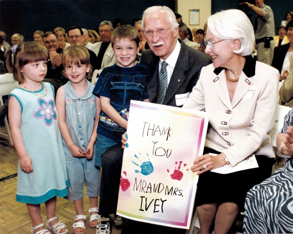 Elderly couple holds up a thank you sign given to them by three children