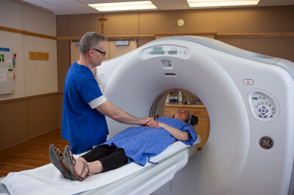 A medical imaging technologist comforts a patient undergoing a CT scan.