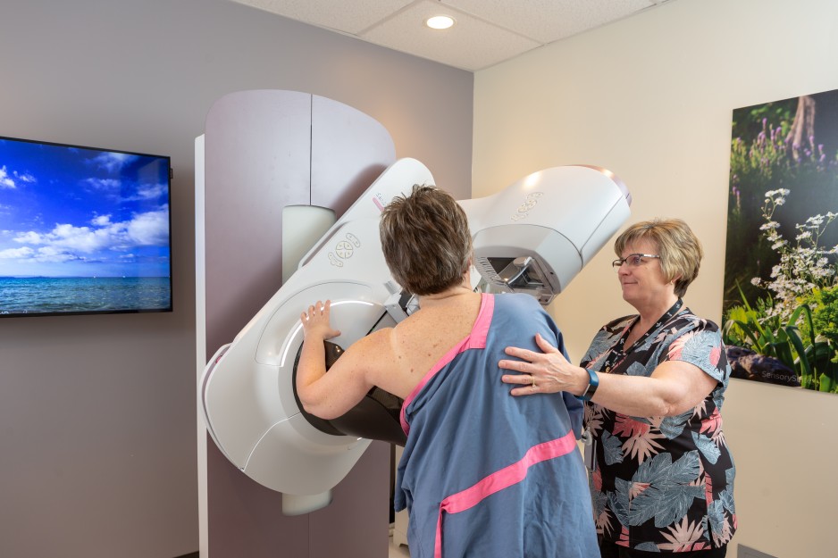A health care provider helps a patient with breast screening.