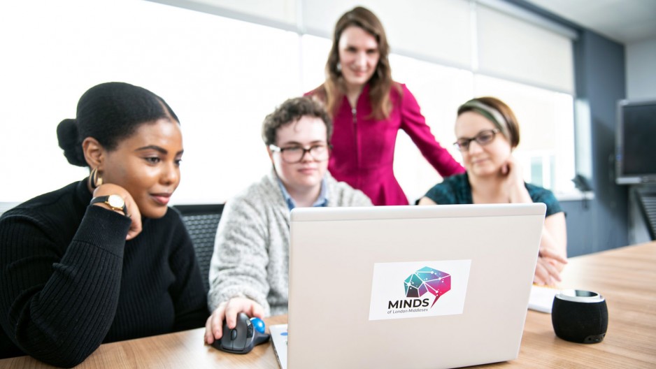 group of people gather around a computer