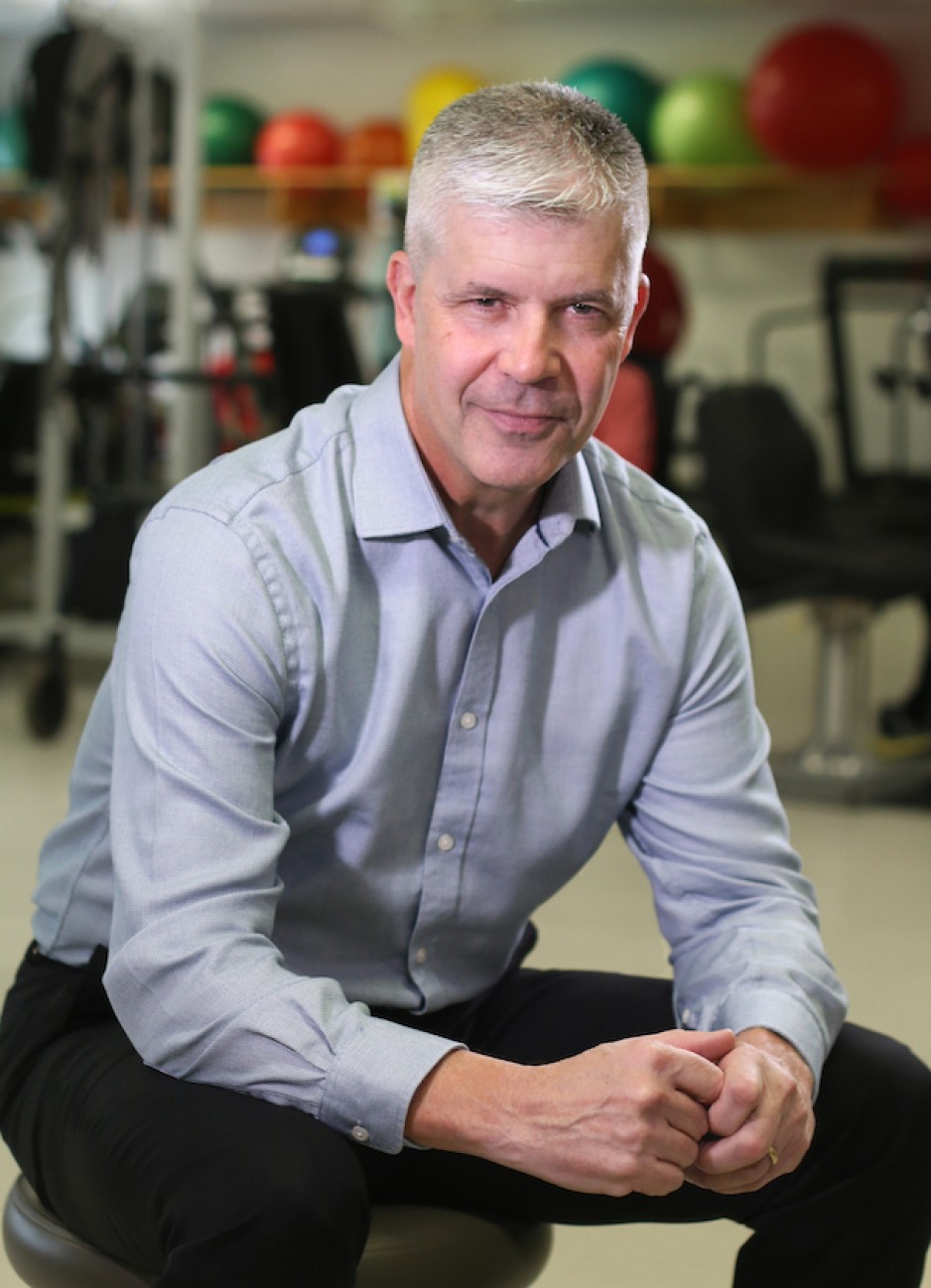 Dr. Doherty sitting, leaning forward with hand touching in front
