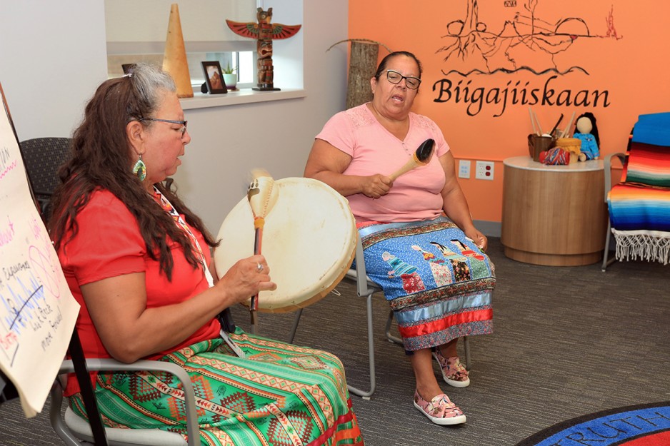  two Indigenous women beating hand-held drums