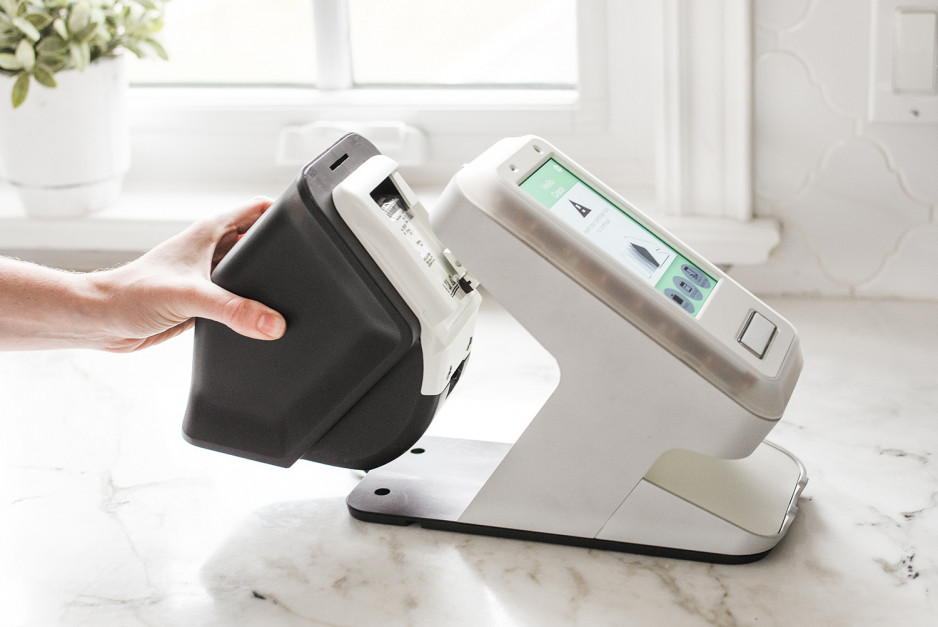 hand grasping back of smart home technology device with data input pad mounted on a stand