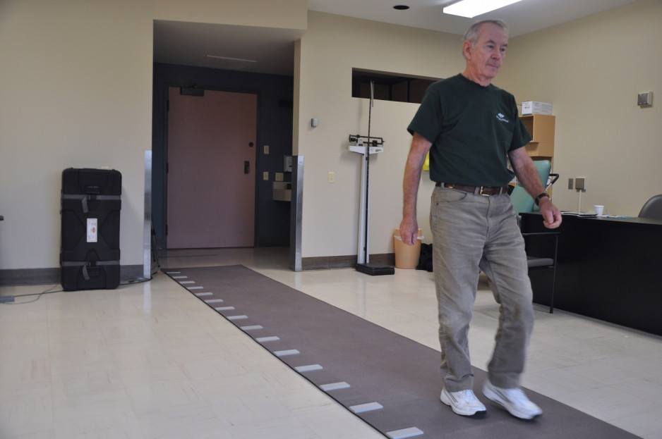 man walking along a path marked with lines every foot, in a researcher's clinic room