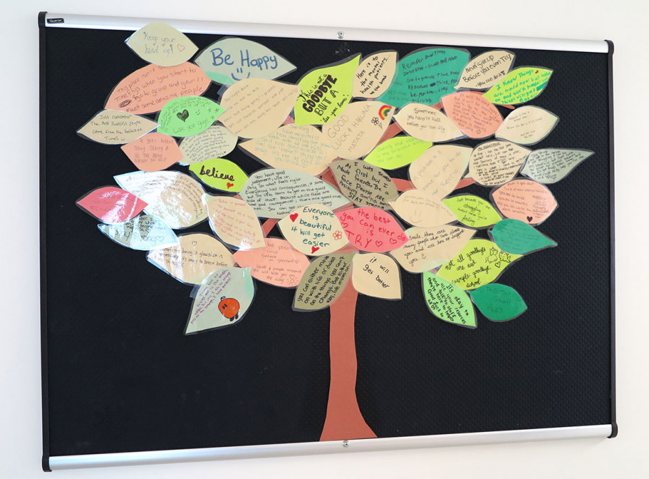a tree with leaf-shaped pieces of paper forming the foliage, and an inspirational message on each leaf