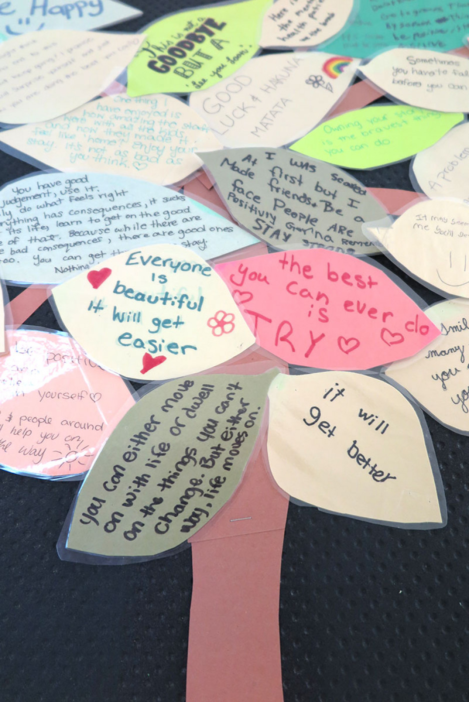 a grouping of leaves with handwritten messages of hope like "It will get better."