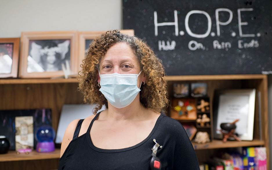 Trish Travis standing in front of a sign that says HOPE - Hold On Pain Ends