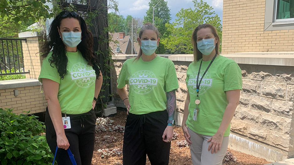 three members of a volunteer vaccination team wearing matching T-shirts