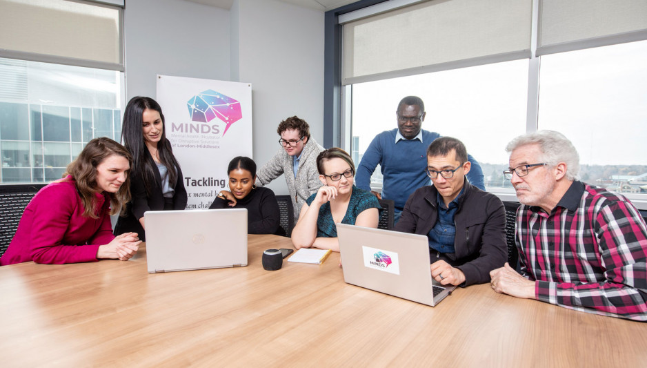 a group of people gathered around two laptop computers