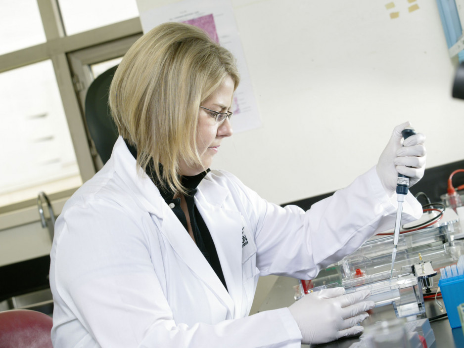 Female scientist adding sample to test tube