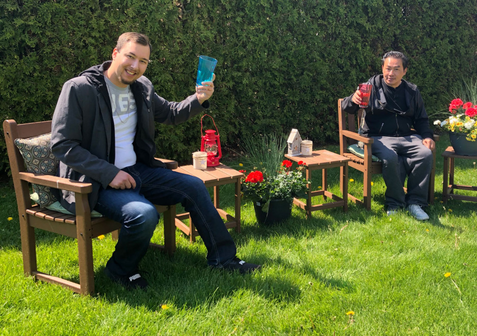 two men raising their drinks while sitting outside